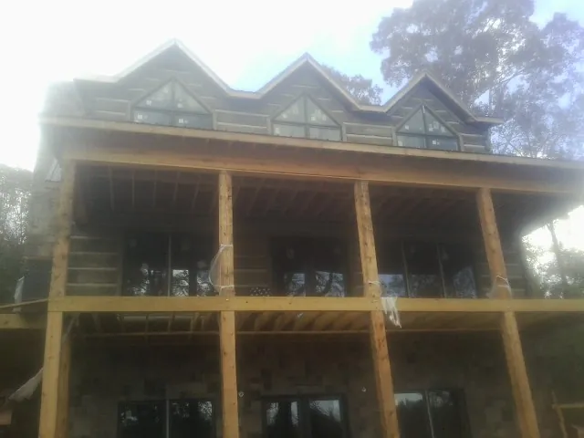 Dormers and porch framing on a large log home under construction — Roof Coating work by our crew in Milton